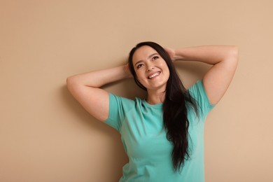 Photo of Beautiful overweight woman with charming smile on beige background