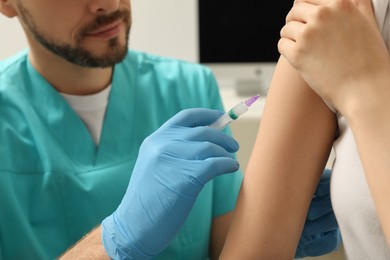 Photo of Doctor giving hepatitis vaccine to patient in clinic, closeup