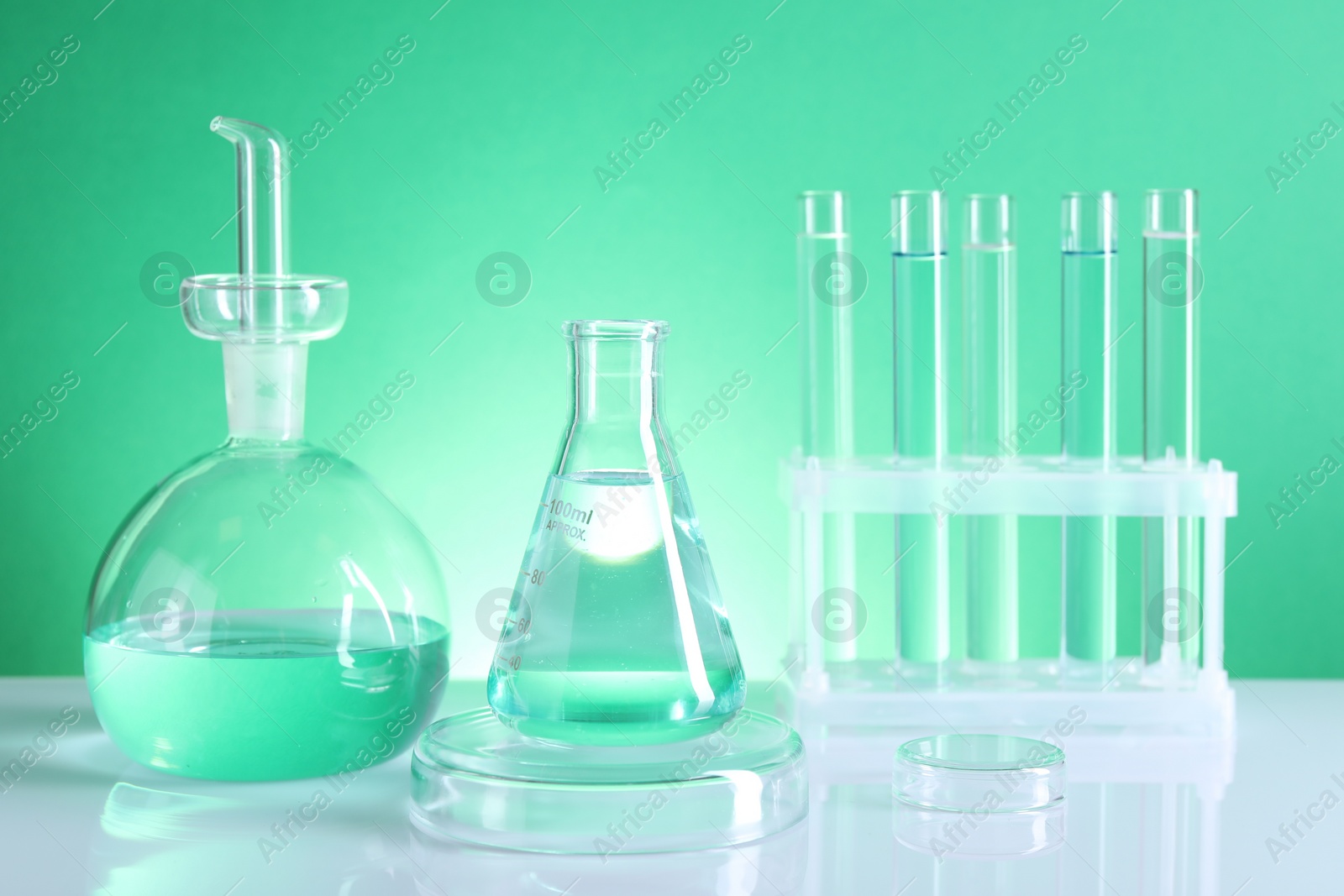 Photo of Laboratory analysis. Different glassware on table against green background