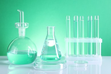 Laboratory analysis. Different glassware on table against green background