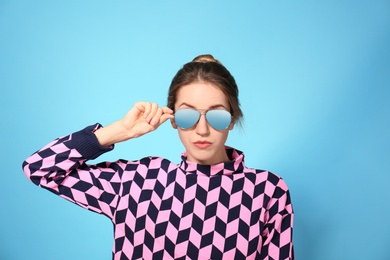 Photo of Young woman wearing stylish sunglasses on blue background