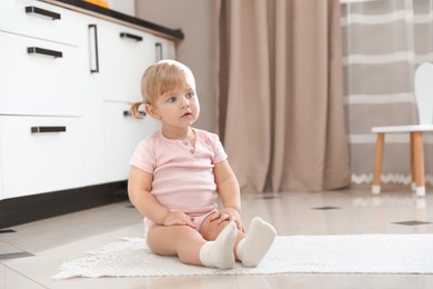 Photo of Cute little child sitting on floor at home