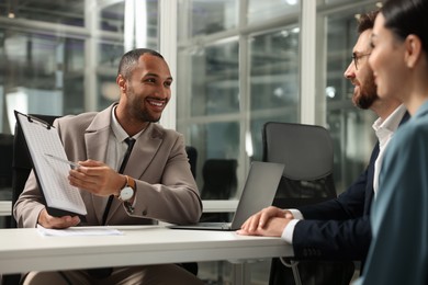 Lawyer with clipboard working with clients at table in office