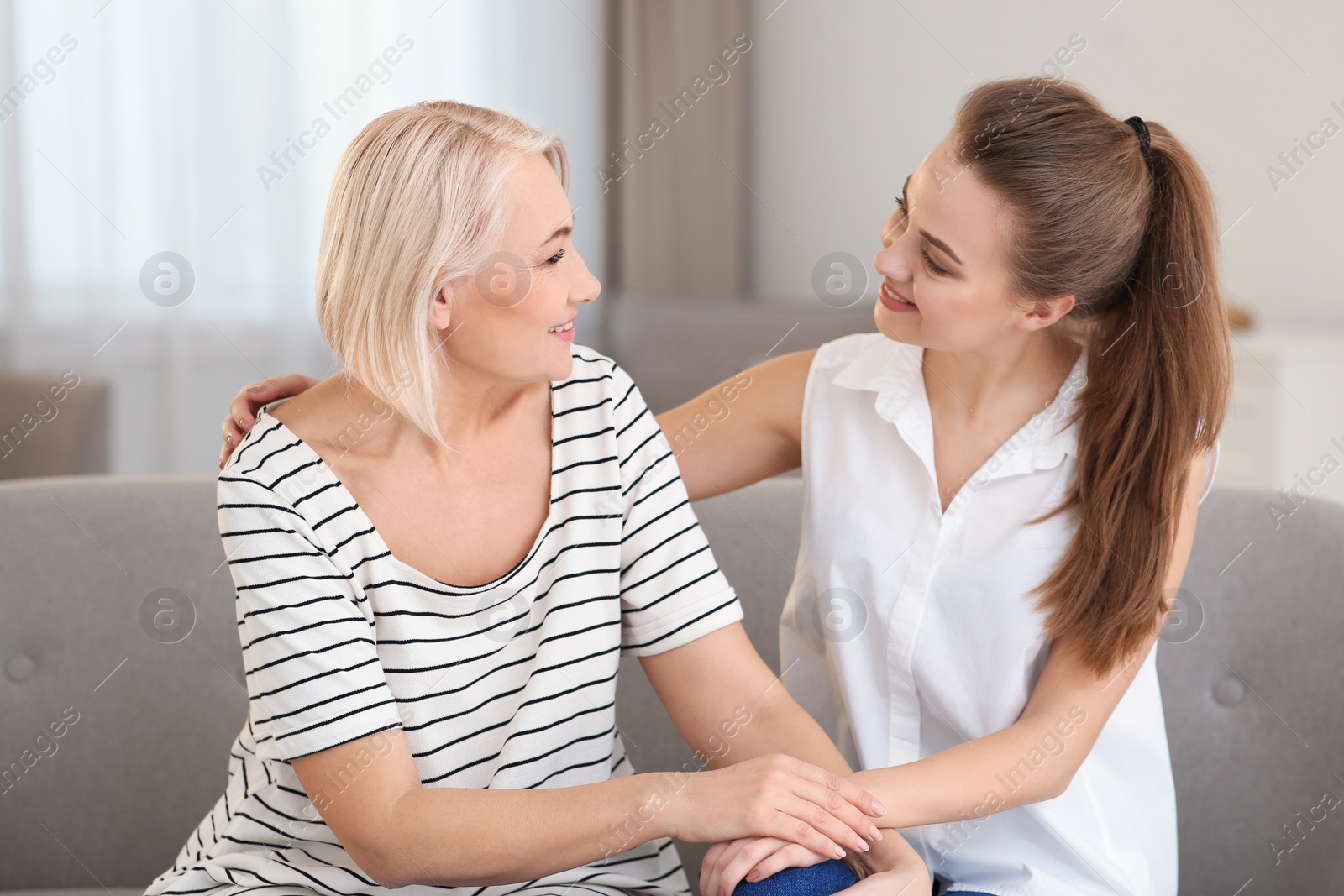 Photo of Portrait of mature woman and her daughter on sofa in living room