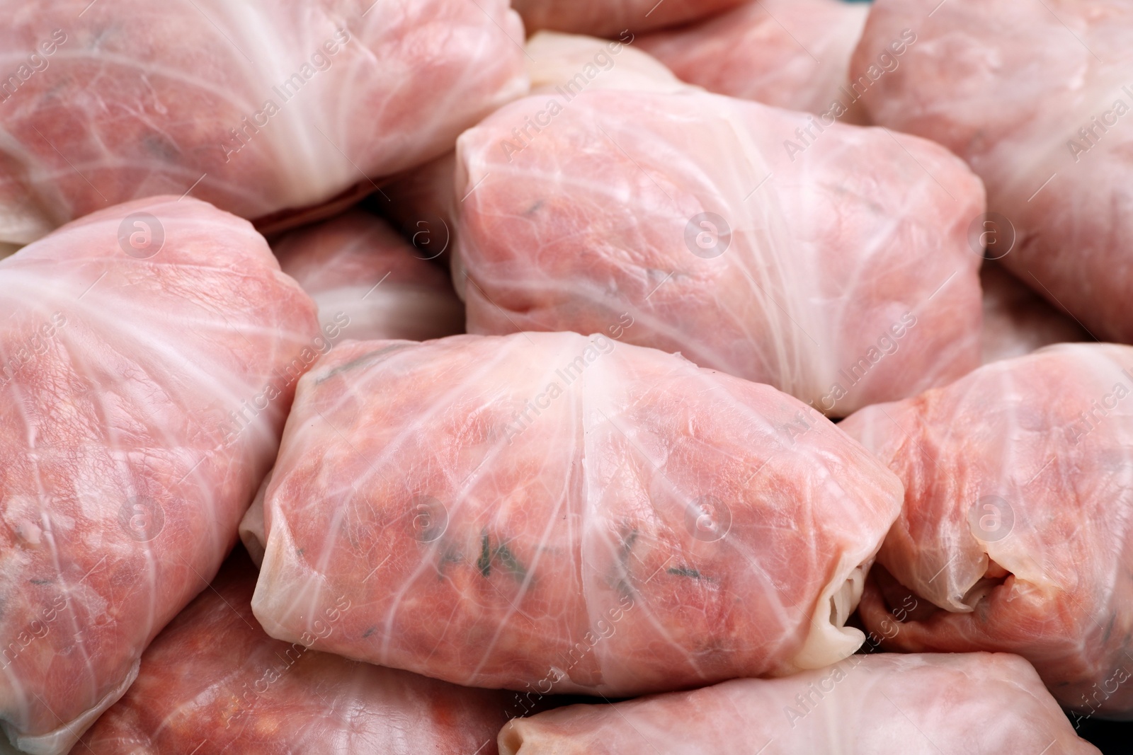 Photo of Uncooked stuffed cabbage rolls as background, closeup view