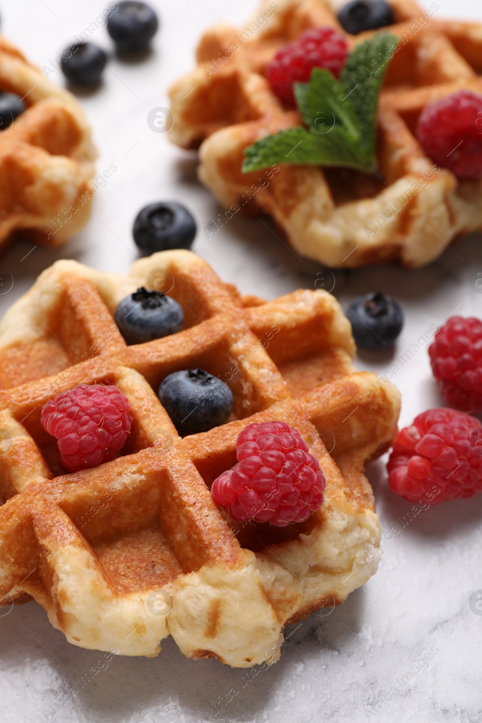 Photo of Delicious Belgian waffles with fresh berries and mint on white table, closeup