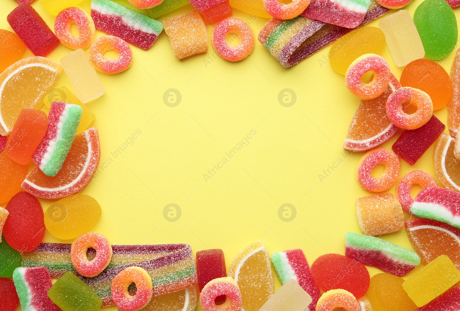 Photo of Frame made with tasty jelly candies on color background, top view. Space for text