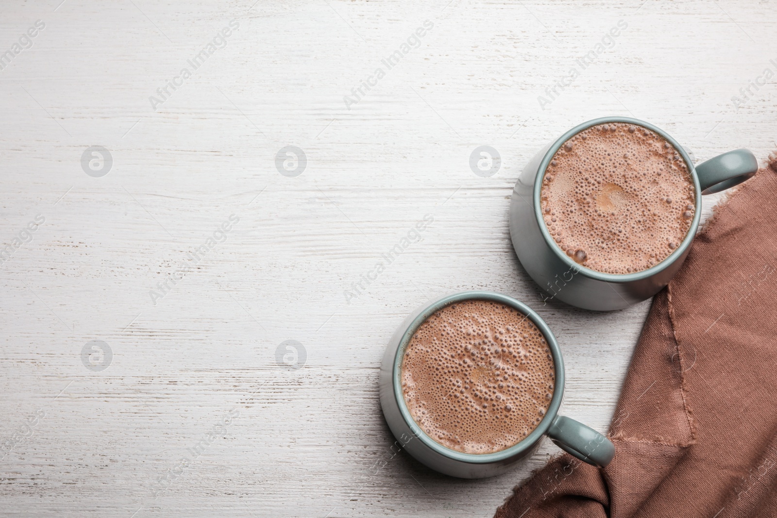 Photo of Cups of delicious hot cocoa on white wooden table, flat lay. Space for text