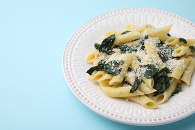 Tasty pasta with spinach and cheese on light blue table. Space for text