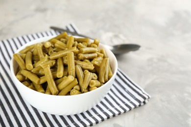Canned green beans in bowl on grey table, closeup. Space for text