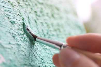 Photo of Artist painting on canvas with brush, closeup