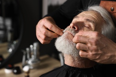Photo of Professional barber working with client's mustache in barbershop, space for text