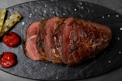 Grilled meat with garnish on slate board, top view