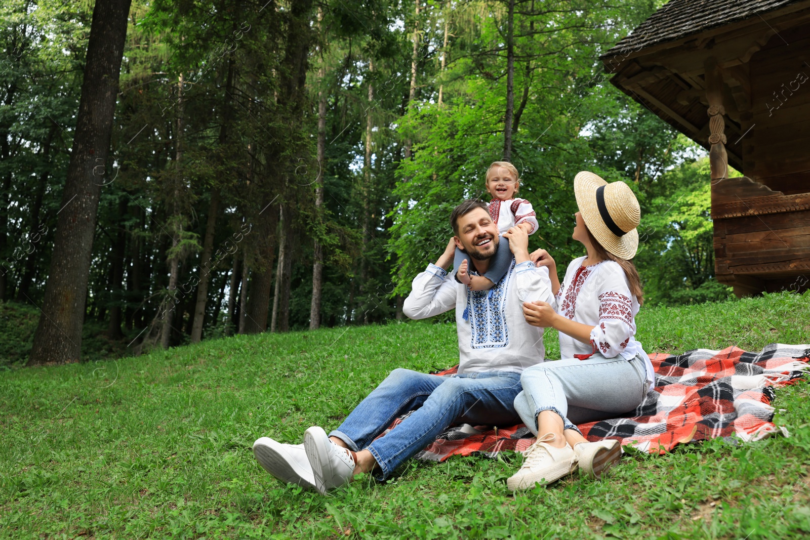 Photo of Happy family in Ukrainian national clothes on green grass outdoors