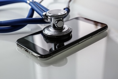 Photo of Smartphone and stethoscope on light table, closeup. Repairing service