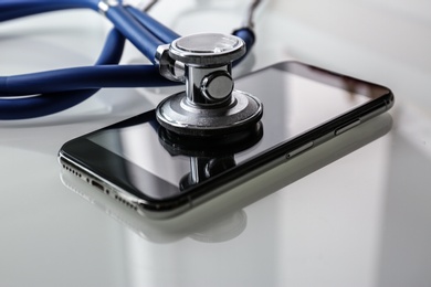 Smartphone and stethoscope on light table, closeup. Repairing service