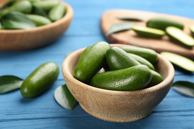 Photo of Fresh seedless avocados in bowl on blue wooden table