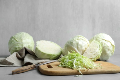 Photo of Whole and cut cabbages on grey table
