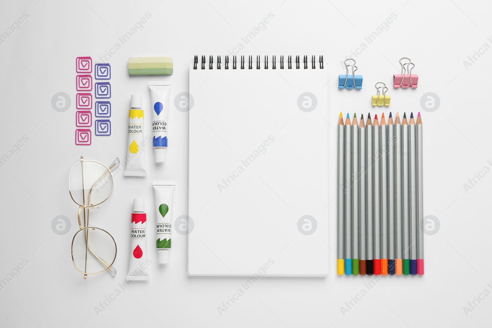 Photo of Composition with sketchbook, glasses and drawing tools on white background, top view