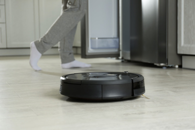 Photo of Modern robotic vacuum cleaner and blurred woman on background