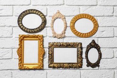 Photo of Blank vintage frames hanging on white brick wall. Mockup for design