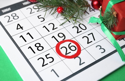 Photo of Calendar with marked Boxing Day date and gift on green background, closeup