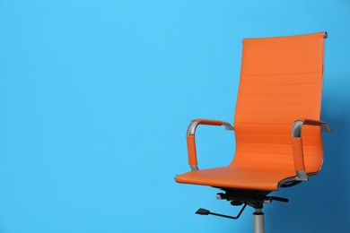 Comfortable office chair on light blue background, space for text