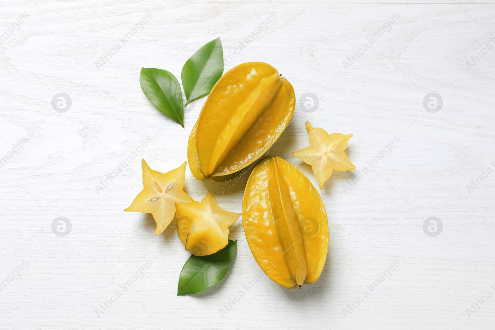 Photo of Delicious carambola fruits on white wooden table, flat lay