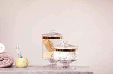 Photo of Composition of glass jar with cotton pads on table near light wall