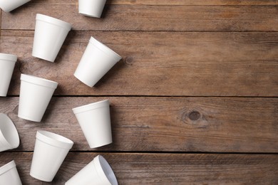 Photo of Many white styrofoam cups on wooden table, flat lay. Space for text