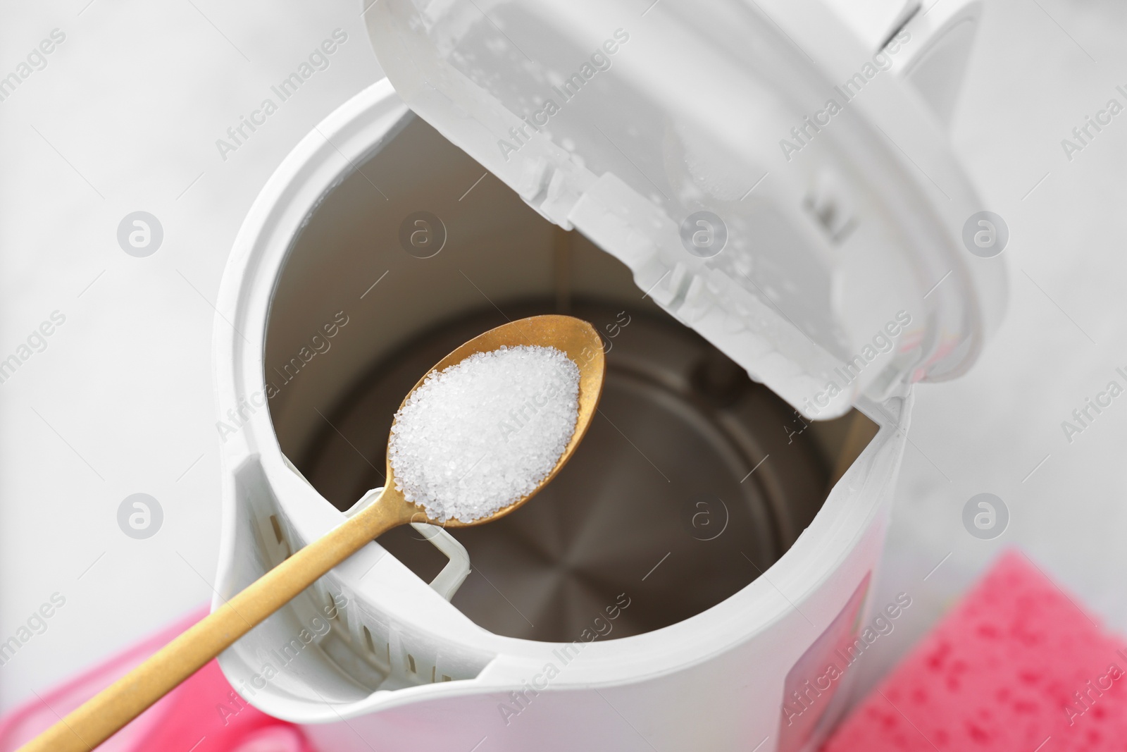 Photo of Cleaning electric kettle. Adding baking soda to appliance at table, above view