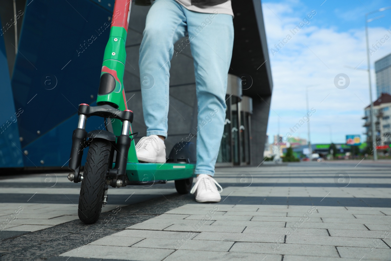 Photo of Man with modern electric kick scooter on city street, closeup. Space for text