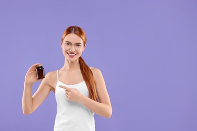 Happy young woman with bottle of pills on purple background, space for text. Weight loss