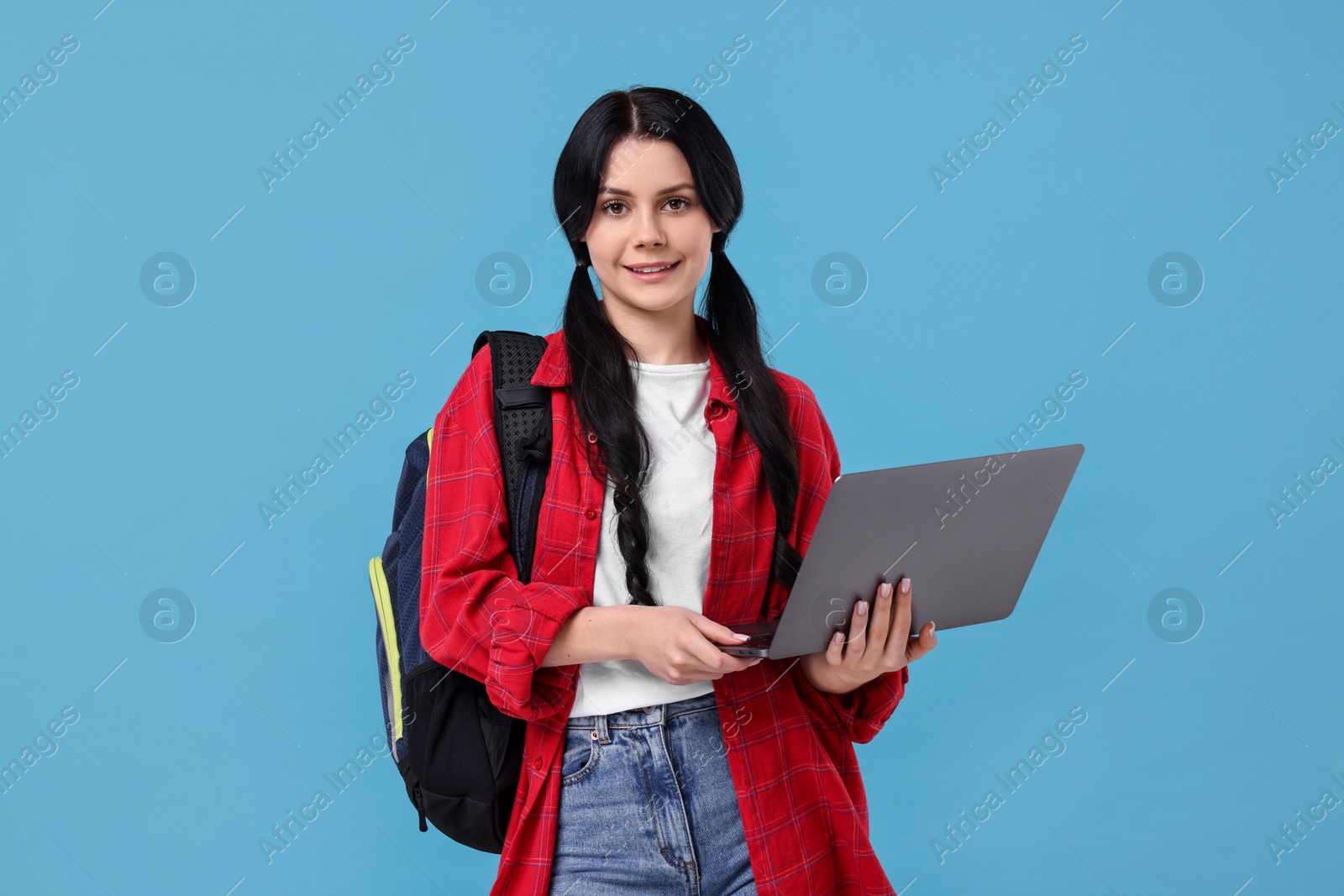 Photo of Smiling student with laptop on light blue background