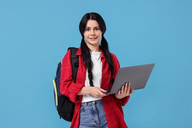 Photo of Smiling student with laptop on light blue background