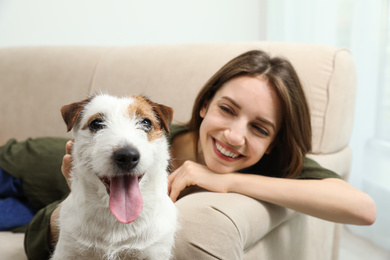 Photo of Young woman with her cute Jack Russell Terrier on sofa at home. Lovely pet