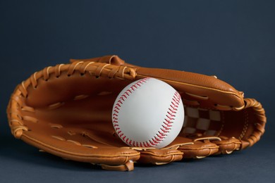 Photo of Catcher's mitt and baseball ball on dark background. Sports game