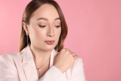 Photo of Young woman with lip and ear piercings on pink background