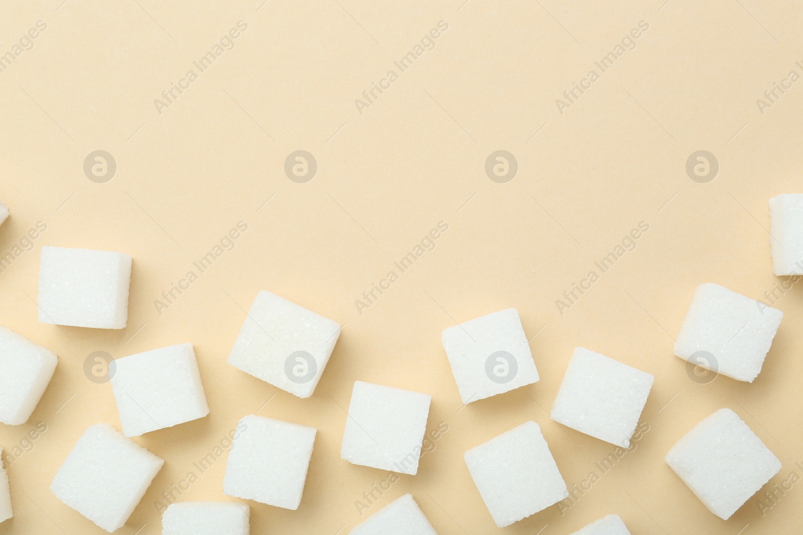 Photo of White sugar cubes on beige background, top view. Space for text