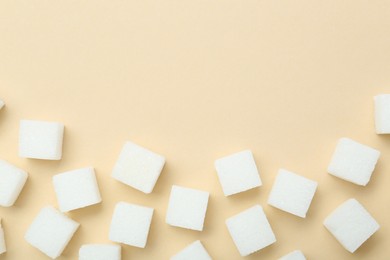 Photo of White sugar cubes on beige background, top view. Space for text