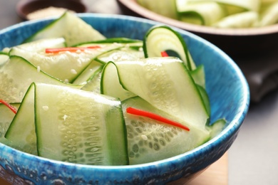 Photo of Dish with fresh cucumber salad on table, closeup