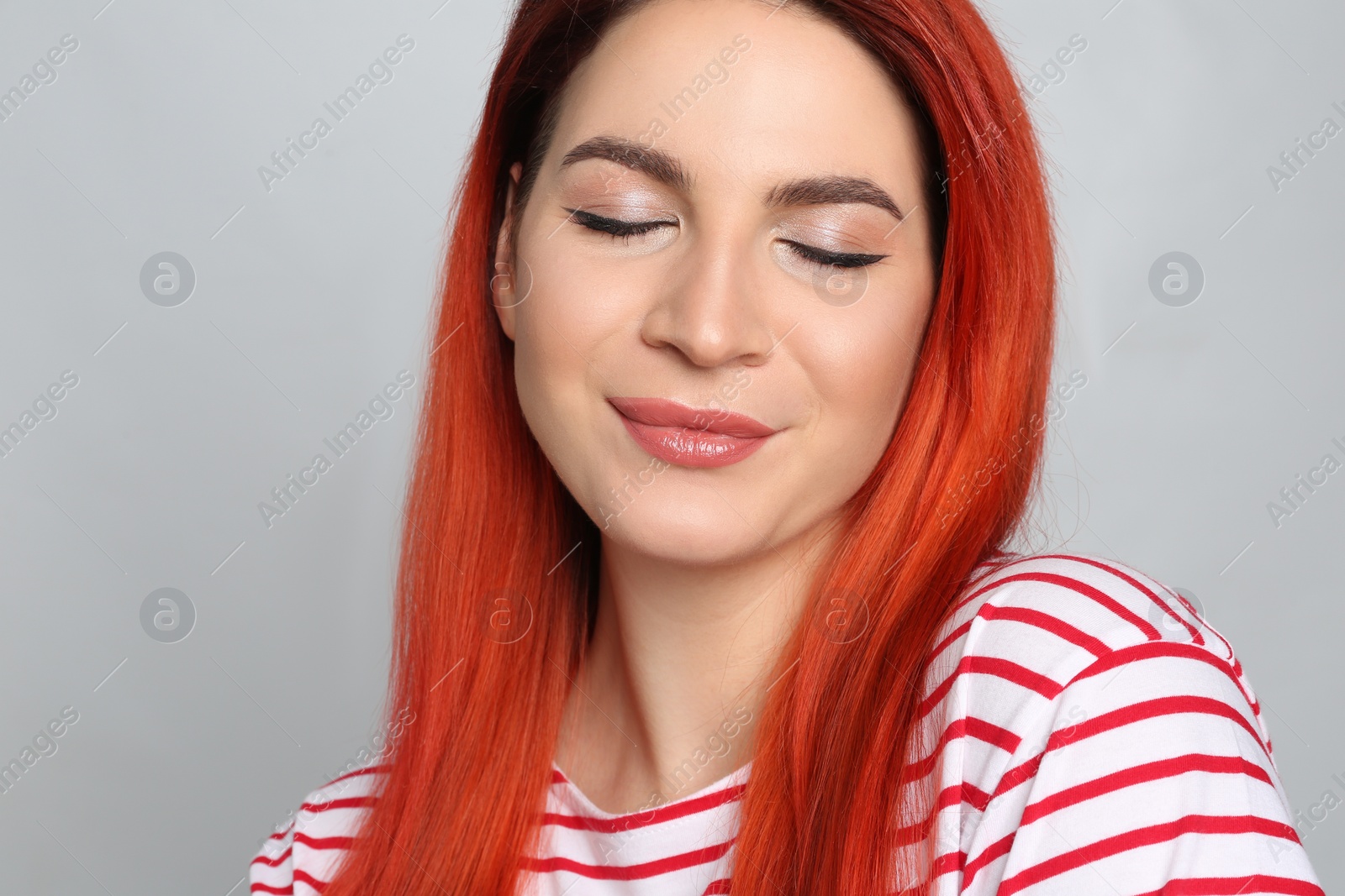 Photo of Young woman with bright dyed hair on grey background, closeup