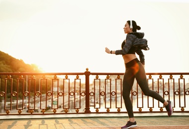 Beautiful sporty young woman running in city