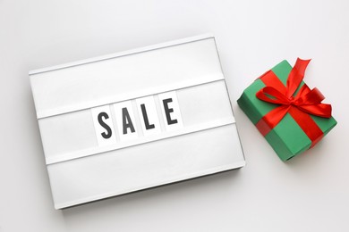Photo of Light box with word Sale and gift on white background, top view