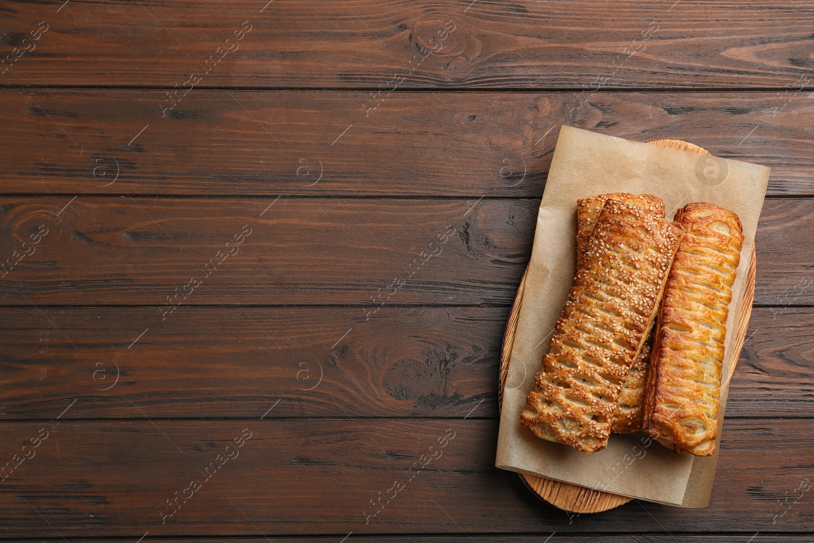 Photo of fresh delicious puff pastry on wooden table, top view. Space for text