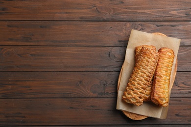 Photo of fresh delicious puff pastry on wooden table, top view. Space for text