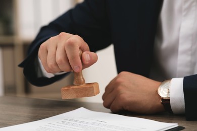 Photo of Man stamping document at table, closeup view