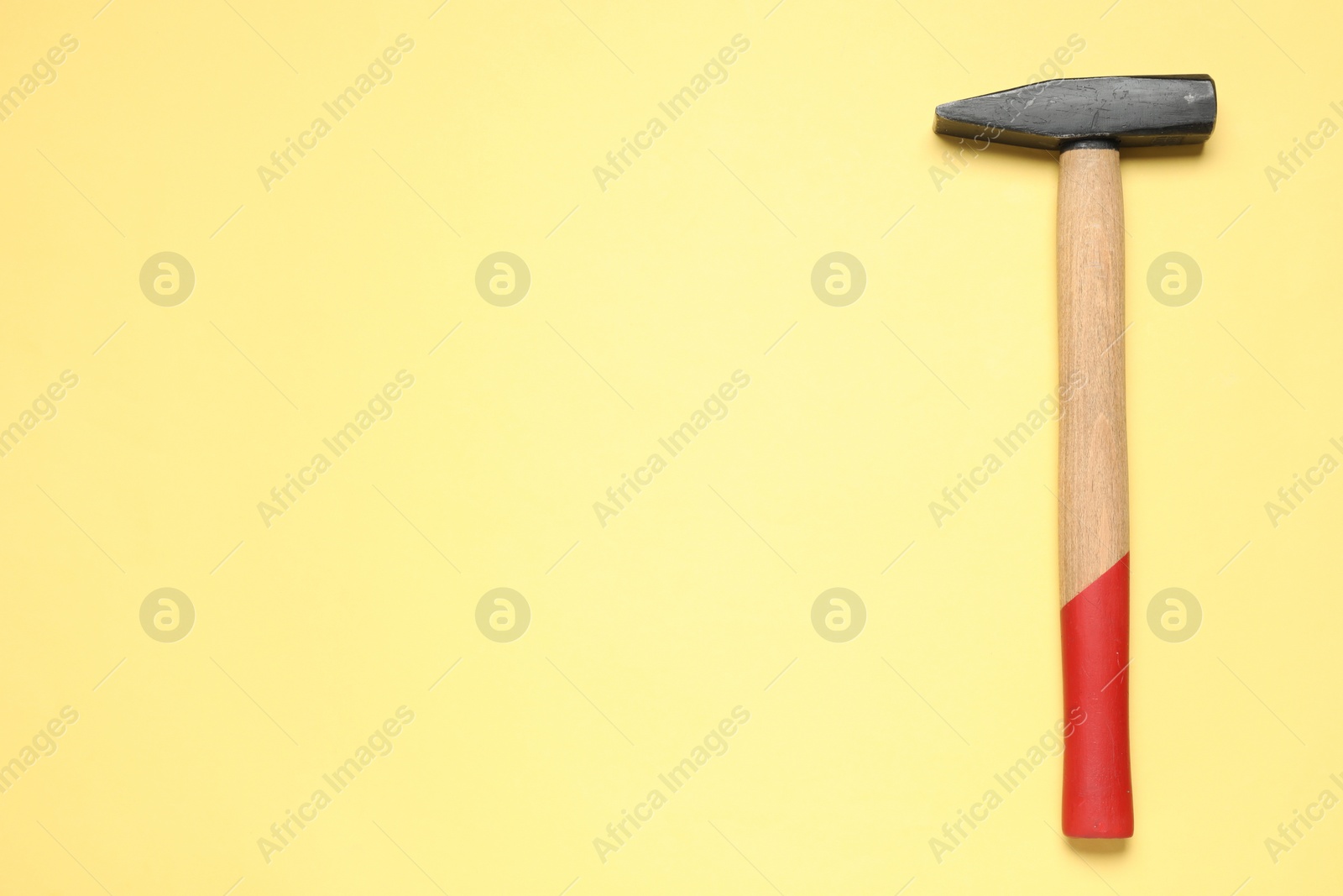 Photo of New hammer with wooden handle on yellow background, top view. Space for text