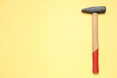 New hammer with wooden handle on yellow background, top view. Space for text