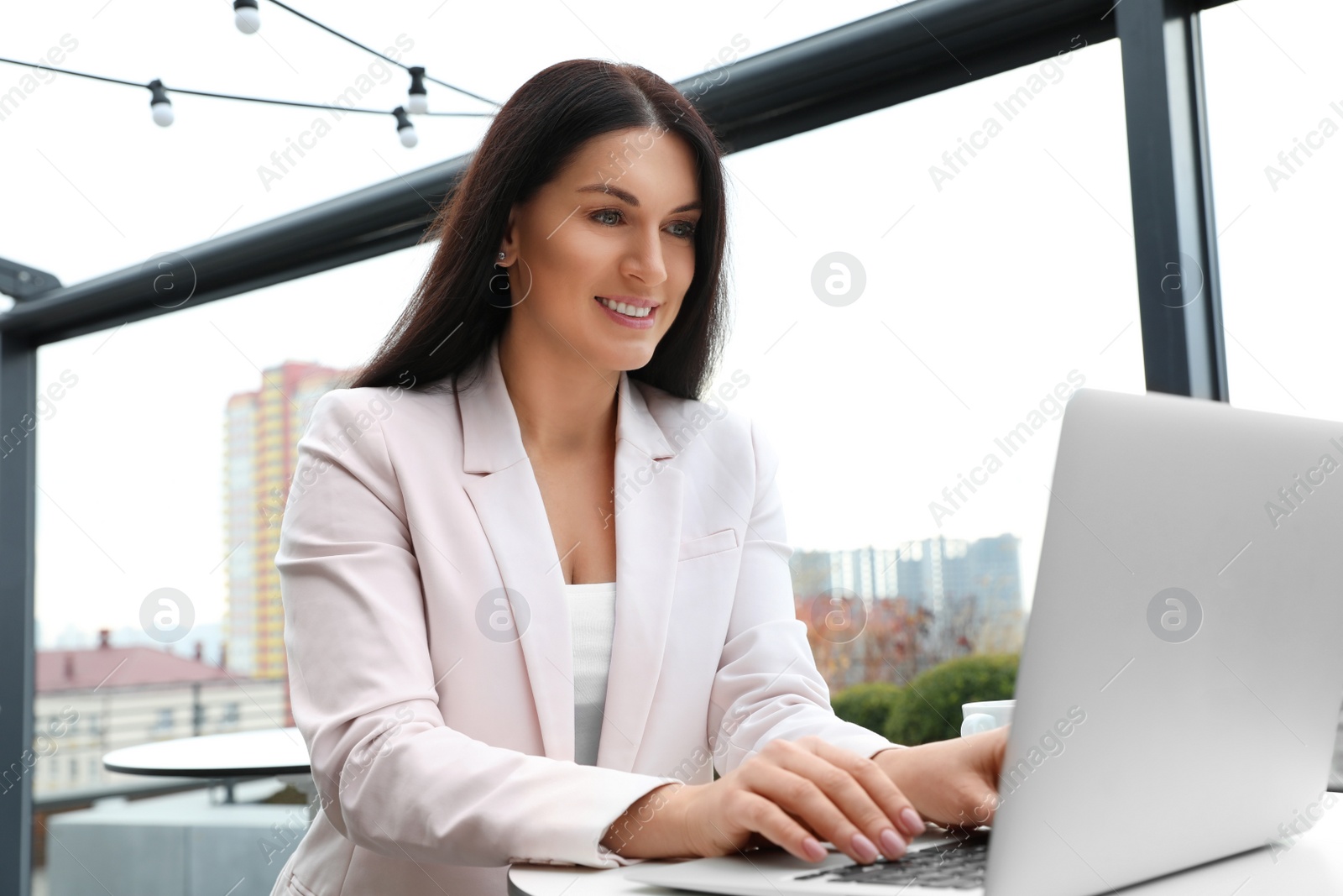 Photo of Businesswoman working with laptop in outdoor cafe. Corporate blog